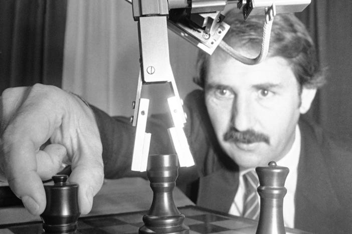 A robot plays a game of chess against a man in 1985.