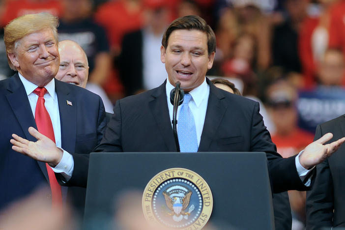 Then-President Donald Trump looks on as Florida Gov. Ron DeSantis speaks during the Florida Homecoming rally at the BB&T Center in 2019.