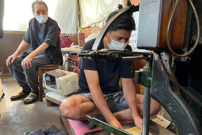 Yoshikazu Netsuno (left) watches his son Shinichi hammer a thick stack of specialized paper. In between each sheet is a thin layer of gold leaf. "My son is going to take over this business, so in our case, we had a successor," Netsuno says. "Many other artisans' families in Kanazawa were not so lucky."