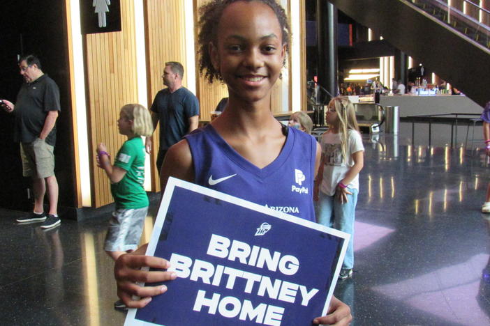 Zariyah Odom holds a sign calling for Griner to return home. Odom had just dropped off shoes for a charity effort that Griner has spearheaded.