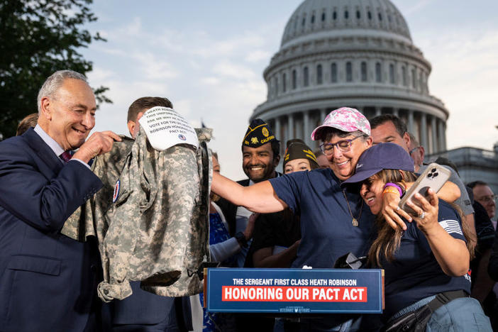 Senate Majority Leader Chuck Schumer (D-N.Y.) looks on Tuesday as Susan Zeier, mother-in-law of the late Sgt. First Class Heath Robinson, hugs Rosie Torres, wife of veteran Le Roy Torres, who suffers from illnesses related to his exposure to burn pits in Iraq, after the Senate passed the PACT Act at the U.S. Capitol in Washington.
