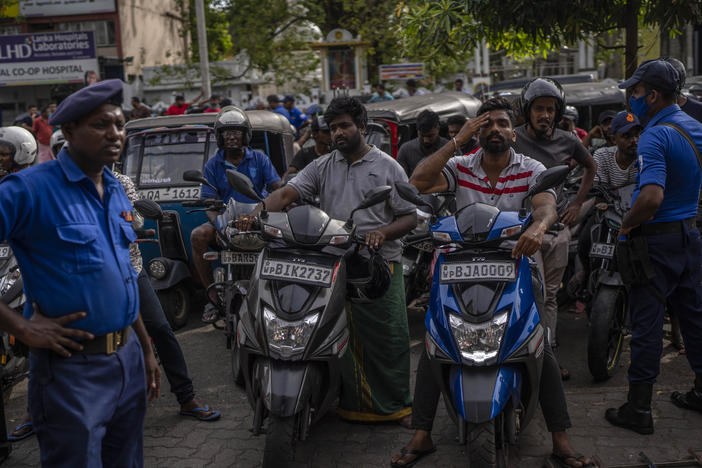 Police officers stand guard as people wait in queue to buy petrol at a fuel station, in Colombo, Sri Lanka, July 17, 2022.