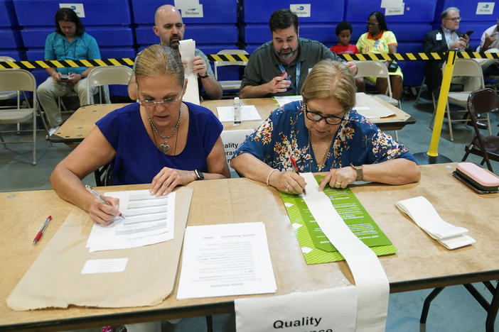 Miami-Dade County Elections Department employees check the tabulation made by voting equipment that will be used in the upcoming state primary election.