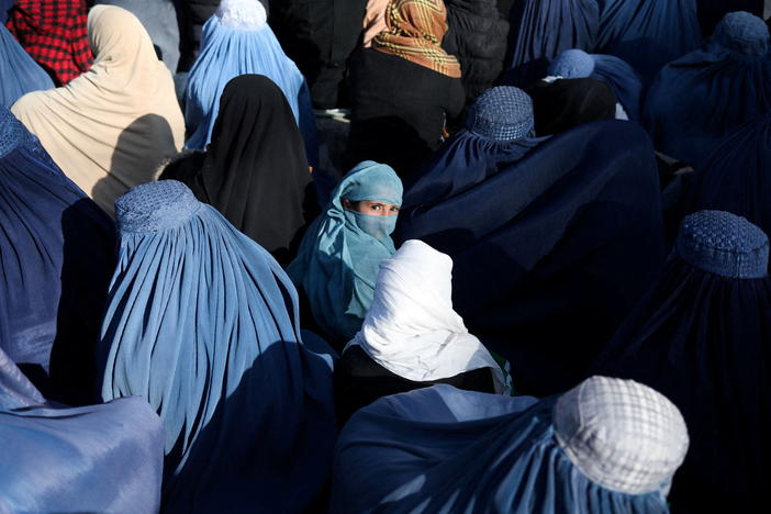 A girl sits in front of a bakery in the crowd with Afghan women waiting to receive bread in Kabul on Jan. 31, 2022.