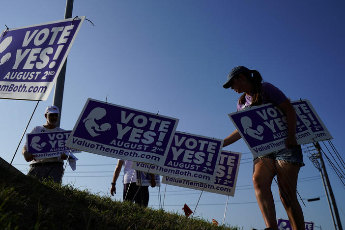 Supporters of a constitutional amendment about abortion in Kansas remove signs ahead of Tuesday's vote.