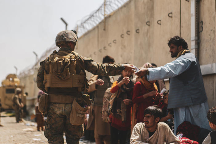 This handout image shows a Marine passing out water to evacuees during an evacuation at Hamid Karzai International Airport, Kabul, Afghanistan, Aug. 22.
