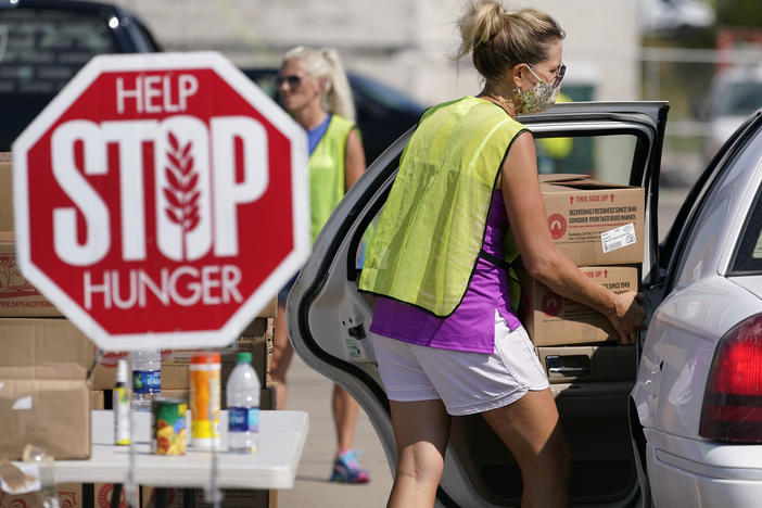 A volunteer loads a local resident's vehicle at a drive-up produce giveaway organized by a Des Moines food pantry on Aug. 28, 2020, in Des Moines, Iowa.