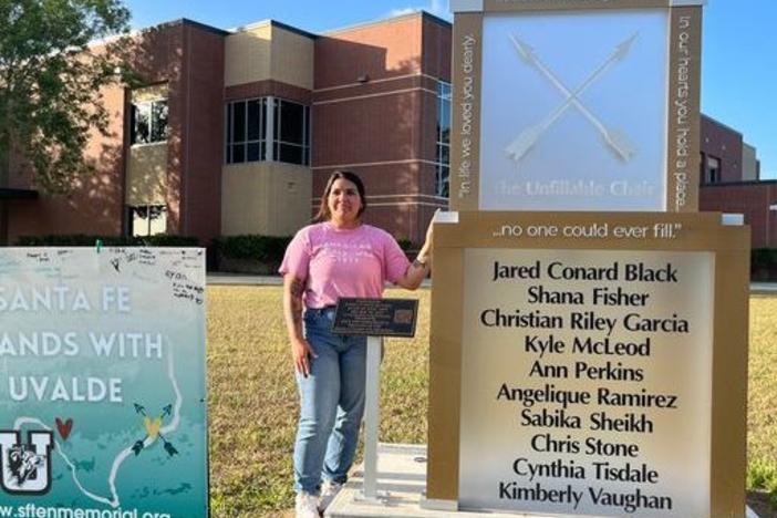 Reagan Gaona stands beside the Unfillable Chair memorial in front of Santa Fe High School in Texas. The memorial is dedicated to the eight students and two teachers killed in a May 2018 shooting. To the left is a sign displaying solidarity with Uvalde, Texas, a city that experienced a similar school shooting in May 2022.