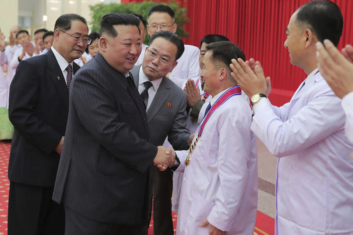 In this photo provided by the North Korean government, North Korean leader Kim Jong Un shakes hands with a health official in Pyongyang, North Korea, Wednesday, Aug. 10, 2022.