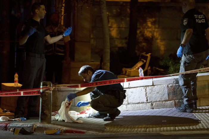 Israeli police crime scene investigators work at the scene of a shooting attack that wounded several Israelis near the Old City of Jerusalem, early Sunday, Aug. 14, 2022.