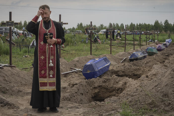 A priest prays for unidentified civilians killed by Russian troops in Bucha, on the outskirts of Kyiv, Ukraine, Aug. 11. Eleven unidentified bodies exhumed from a mass grave were buried in Bucha that day.
