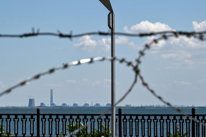 The Zaporizhzhia nuclear power plant in Ukraine's Enerhodar, Zaporizhzhia region, is seen through barbed wire on the embankment in Nikopol, Dnipropetrovsk region, central Ukraine, on July 20. Russian soldiers have been shelling Nikopol from the premises of the nuclear power plant.