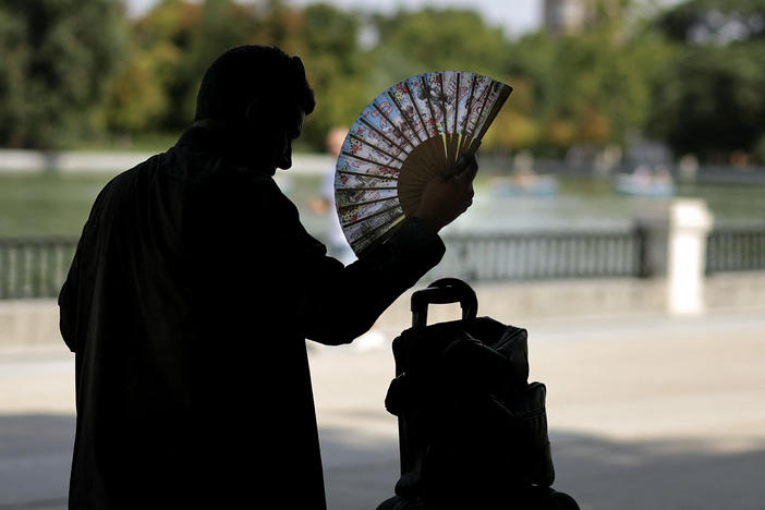 A man uses a hand fan in a park in central Madrid during a heat wave.