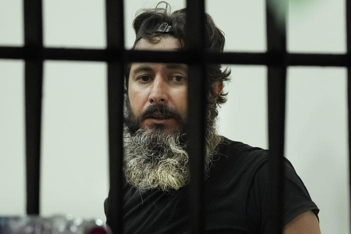 Bassam al-Sheikh Hussein looks through the bank's window in Beirut, Lebanon during the hostage standoff on Thursday. He surrended after several hours of negotiations in exchange for a portion of his savings.