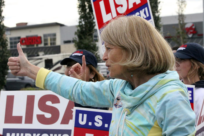 U.S. Sen. Lisa Murkowski, an Alaska Republican, flashes a thumbs up to a passing motorist while waving signs Tuesday in Anchorage.