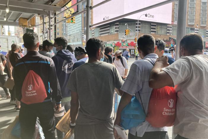 Asylum-seekers who have recently arrived in New York on a bus from Texas wait for ride-share vehicles, organized by a mutual aid group, to take them into the city.