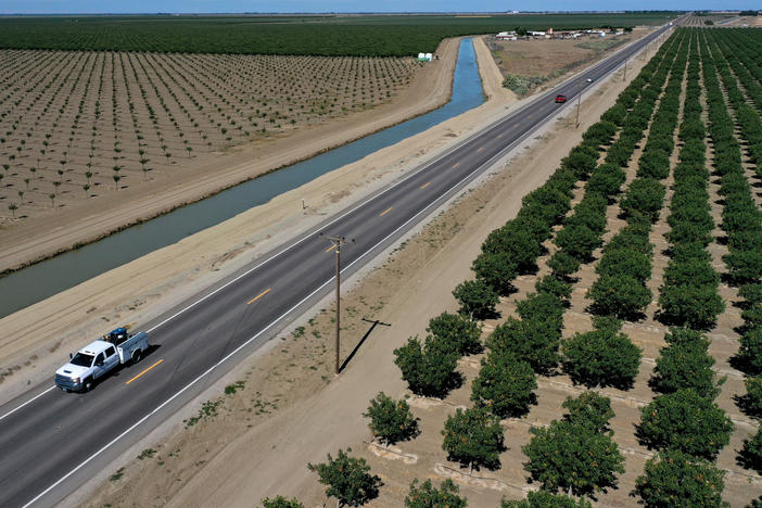 A vehicle drives by an almond orchard in Firebaugh, Calif., last year. City manager Ben Gallegos told NPR he doesn't want small cities like his to be overlooked as California prepares for a potential megastorm, a weather event made more likely by climate change.
