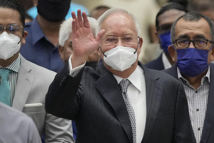 Former Malaysian Prime Minister Najib Razak, center, wearing a face mask, waves as he arrives at the Court of Appeal in Putrajaya, Malaysia, Tuesday, Aug. 23, 2022.