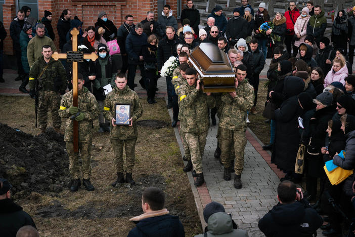 A funeral procession in Lviv, Ukraine, in March ends at grave sites where soldiers Viktor Dudar, 44, and Ivan Koverznev, 24, will be buried, as priests say their blessings and mourners look on.