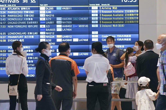 People wearing face masks are seen at an arrival lobby of Haneda airport in Tokyo on Aug. 23, 2022, amid the coronavirus pandemic.