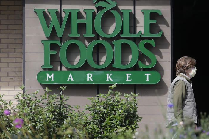 A pedestrian wears a mask while walking past a sign for a Whole Foods Market in San Francisco, Tuesday, March 31, 2020.