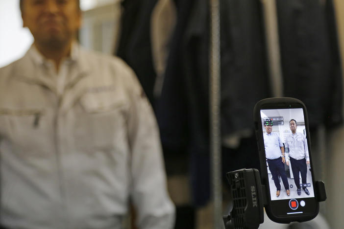 General Manager Tomohiko Kojima takes a TikTok video with CEO Daisuke Sakurai, as seen in the screen of the cell phone, at the Tokyo headquarters office of Daikyo Security Co. in Tokyo Monday, Aug. 22, 2022.