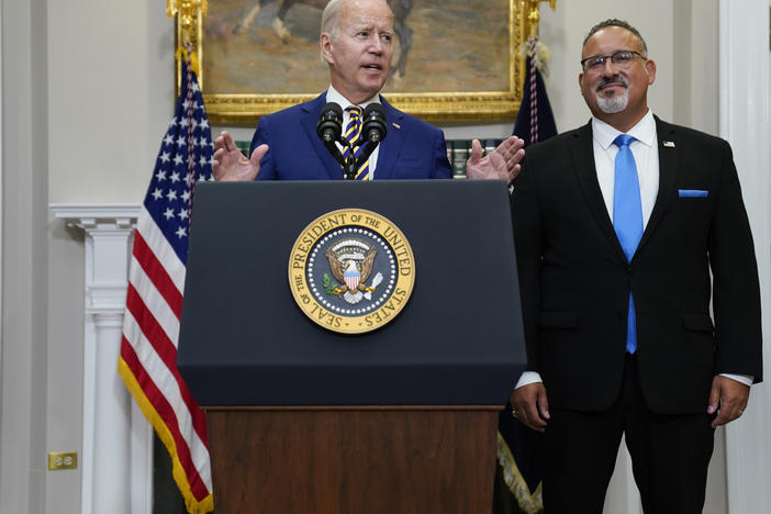President Joe Biden speaks about student loan debt forgiveness in the Roosevelt Room of the White House on Wednesday as Education Secretary Miguel Cardona listens at right.