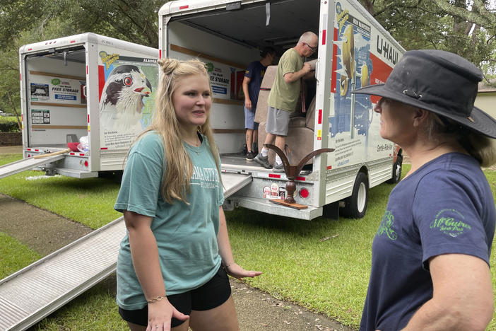 Medical student Emily Davis, left, speaks with her landlord Suzannah Thames on Friday as workers move furniture, appliances and other belongings out of a home Davis and her husband are renting in a flood-prone area of Jackson, Miss.