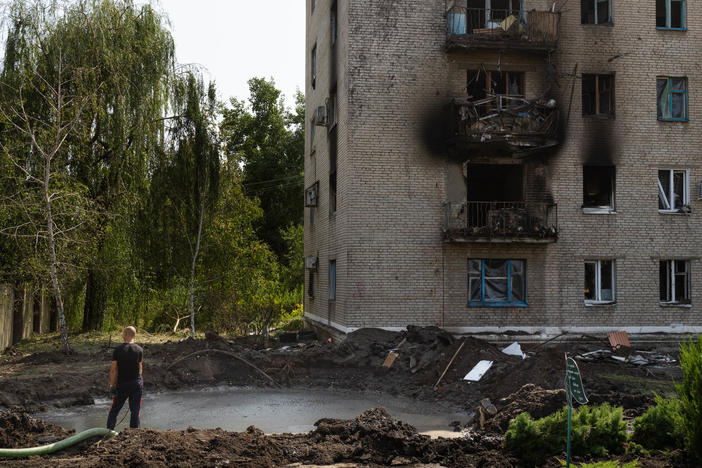 A man stands in front of a crater that was made from a missile strike in Slovyansk on Sunday morning.