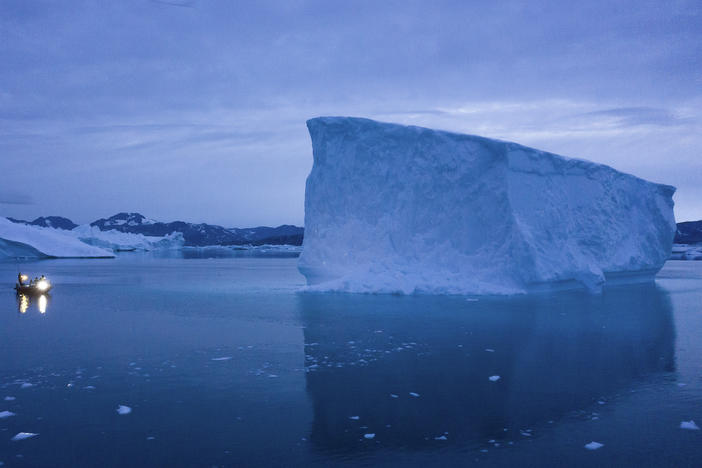 A boat navigates at night next to large icebergs in eastern Greenland on Aug. 15, 2019.