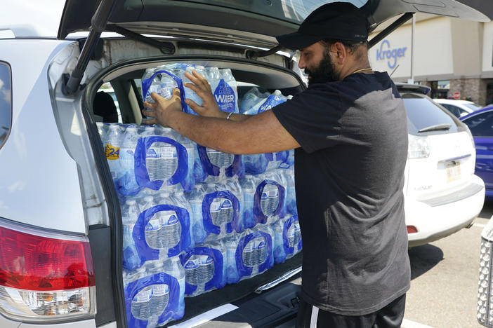 Rajwinder Singh, a gas station/convenience store owner, pats into place the 15 cases of drinking water he purchased from a Kroger grocery store into his vehicle, on Tuesday in Jackson, Miss.