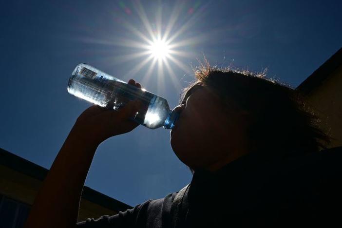 A child sips water from a bottle under a scorching sun on Tuesday in Los Angeles. Forecasters say temperatures  could reach as high as 112 degrees in the densely populated Los Angeles suburbs in the next week as a heat dome settles in over parts of California, Nevada and Arizona.