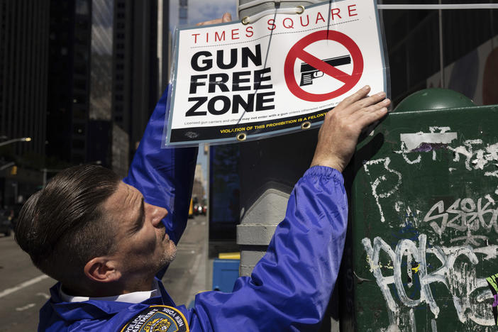 An New York Police Department Public Affairs officer sets up signs reading Gun Free Zone around Times Square, Wednesday, Aug. 31, 2022, in New York.
