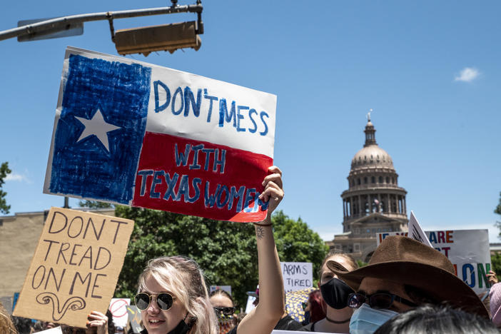 Protesters hold signs as they march in opposition to the anti-abortion law S.B. 8 outside the Texas state capitol on May 29, 2021 in Austin.