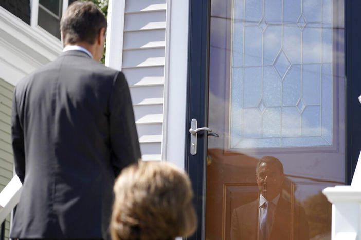 Dan Sideris is reflected in a front storm door Thursday as he and his wife, Carrie Sideris, of Newton, Mass., return to door-to-door visits as Jehovah's Witnesses in Boston. After more than two and a half years on hiatus due to the coronavirus pandemic, members are reviving a religious practice that the faith considers crucial and cherished.