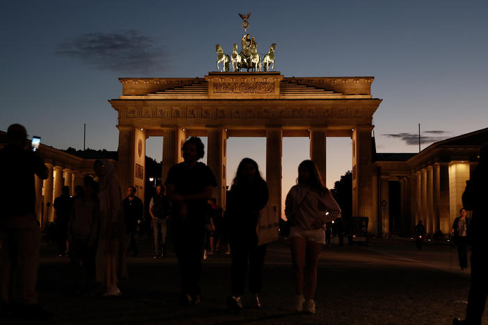 People walk near Berlin's Brandenburg Gate on the day a new law to save energy nationwide goes into effect on Thursday. The new law includes a wide variety of temporary measures, like banning the illumination of landmarks and regulating temperatures in public and private venues, to save electricity. These are a response to inflation and lower natural gas and other energy supplies from Russia.