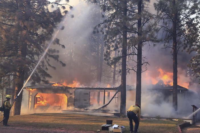 California Department of Forestry and Fire Protection firefighters try to stop flames from the Mill Fire from spreading on a property in the Lake Shastina subdivision northwest of Weed, Calif. on Friday.