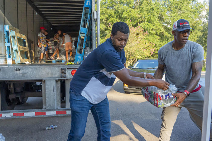 Jarvis Jones and John Knight help distribute free bottled water at the Sykes Park Community Center in Jackson, Mississippi.