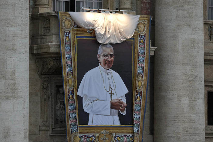 The tapestry depicting late Pope John Paul I hanging from the facade of St. Peter's Basilica, is unveiled during the beatification ceremony led by Pope Francis at the Vatican, Sunday, Sept. 4, 2022.