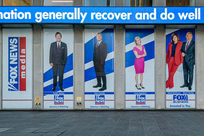 Among the stars being questioned under oath for Dominion Voting Systems' defamation suit against Fox News are Tucker Carlson, Sean Hannity and Maria Bartiromo. Banners bearing their images hang from Fox Corp. headquarters in New York City, first, second and fourth from left, respectively.