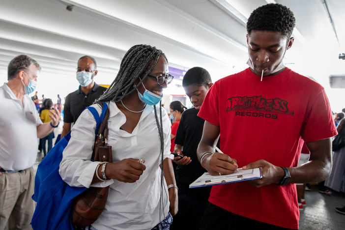Layi Oniwinde, 16, fills out an election worker application as his mother, Adaobi Oniwinde, looks on with a smile in Wheaton, Md. "I love the way the system here allows everybody to be involved," says Adaobi about the U.S. election system.