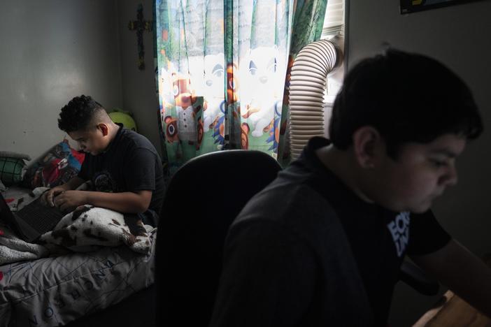 Eloyd, 11, left, plays online video games with his brother Emmanuel, 12, right, at his home in Uvalde, Texas.