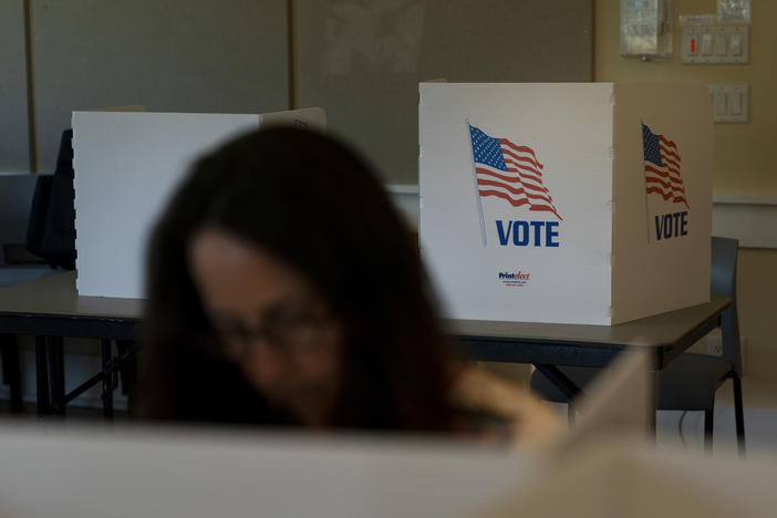 A voter in the foreground casts her ballot during the Republican primary election in Wilson, Wyo., on Aug. 16.