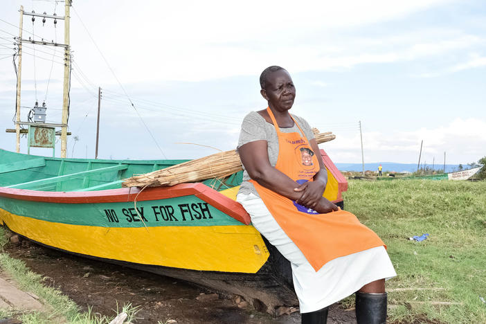 Justine Adhiambo Obura with one of the "No Sex for Fish" boats at Nduru beach. She is the chairperson of the cooperative that came up with a radical idea in a community where fishermen often demanded transactional sex before giving a supply of fish to a woman to sell: What if women had their own boats and hired men to fish for them?