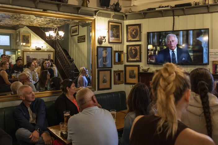 People watch the televised speech of the new King Charles III inside a pub in London, Friday. King Charles III says he feels "profound sorrow" over the death of his mother, Queen Elizabeth II, and vows to carry on her "lifelong service" to the nation.