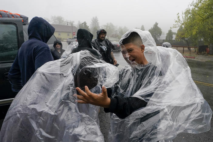 Members of the Ornelas family put on plastic raincoats as wind and rain pummel the area Friday, Sept. 9, 2022, in Julian, Calif. A tropical storm nearing Southern California has brought fierce mountain winds, high humidity, rain and the threat of flooding to a region already dealing with wildfires and an extraordinary heat wave. (AP Photo/Gregory Bull)