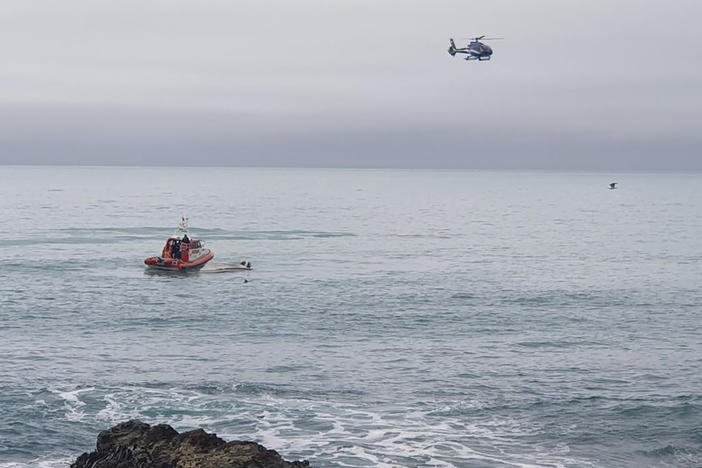 A helicopter and a rescue boat search for survivors off the coast of Kaikoura, New Zealand, on Saturday.