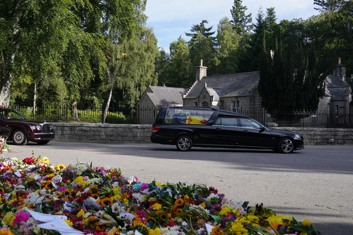 The hearse carrying the coffin of Queen Elizabeth II, draped with the Royal Standard of Scotland, leaves Balmoral as it begins its journey to Edinburgh.