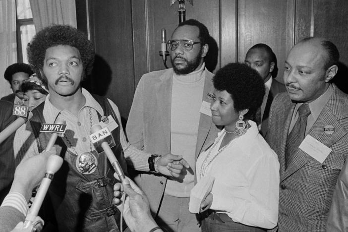 This March 26, 1972 file photo shows the Rev. Jesse Jackson speaking to reporters at the Operation PUSH Soul Picnic in New York as Tom Todd, vice president of PUSH, from second left, Aretha Franklin and Louis Stokes.