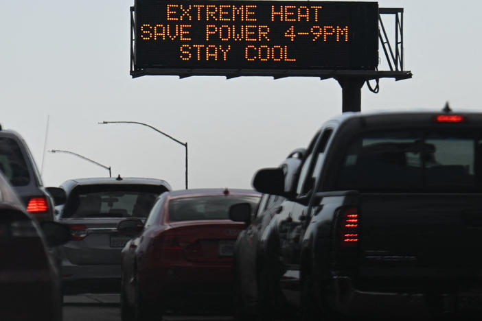 Vehicles drive past a sign on the 110 Freeway warning of extreme heat and urging energy conservation during a heat wave in downtown Los Angeles on Sept. 2. Soaring electricity bills are pinching many household budgets across the country even as gasoline prices have come down.